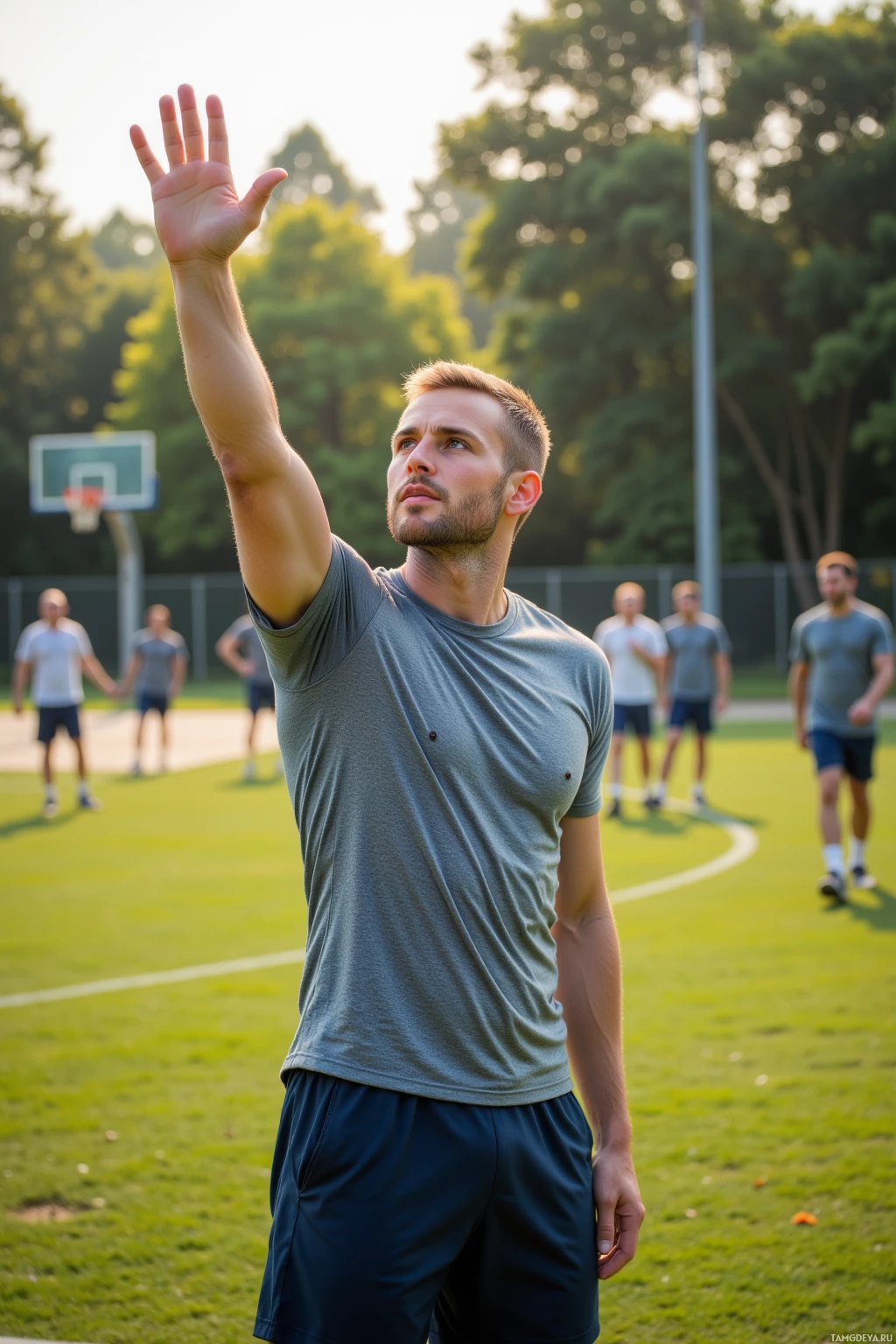 Realistic high quality photo. A 32‑year‑old man with shaved blonde hair, blue eyes, fair skin wearing a fitted grey athletic t‑shirt and dark blue joggers stands on a sunlit grassy basketball court in the morning, mid‑gesture raising his hand to deliver a playful trivia question as teammates laugh and prepare to sprint under the soft green glow of dawn.