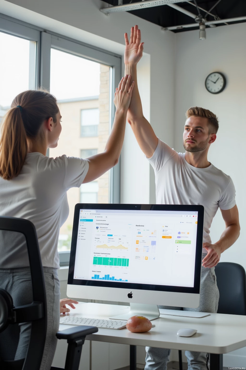 Двое людей похлопывают друг друга по руке, празднуя что-то в офисе.